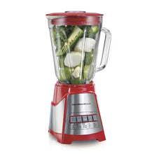 Red blender with clear jar holding green vegetables and white chunks