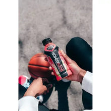 Hand holding BODYARMOR sports drink bottle near basketball