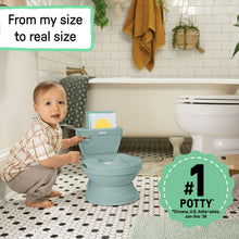 Blue-green toddler potty with open seat while a child stands nearby in bathroom