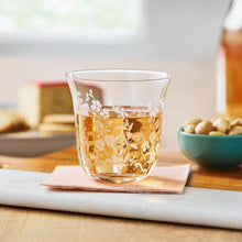 Clear glass tumbler with floral etching, holding an amber beverage