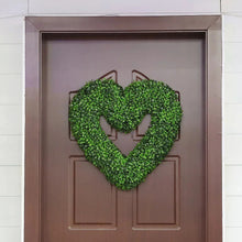 Heart-shaped faux boxwood wreath on door, wrapped around metal heart frame