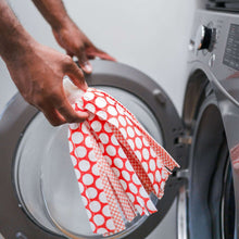Red-and-white patterned microfiber mop cloth lifted near a washing machine