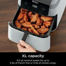 Ninja air fryer basket holding cooked food, white drawer-style basket with black interior