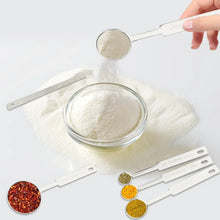Stainless measuring spoon set dispensing powder into a bowl and jar