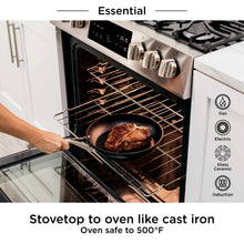 Black nonstick frying pan with long handle placed in oven on wire rack