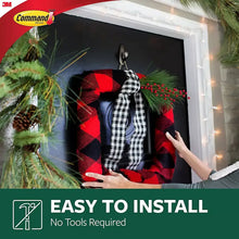 Brushed metal Command hook holding a holiday wreath on a dark surface