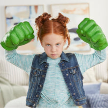 Child with green smash fist glove toy, arms raised in a playful pose