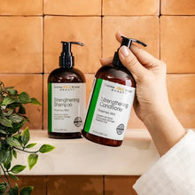 Conditioner and shampoo bottles; hand holding the conditioner pump bottle
