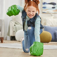 Green smash fist glove toy on the floor while a child stands holding fists