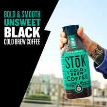 Hand holding cold brew coffee bottle with black cap and turquoise label, unsweetened