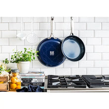 Two blue non-stick frypans hanging on hooks with stainless handles