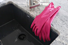 Magenta rubber cleaning glove resting on a sink edge