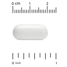 White oval magnesium tablet next to size ruler, showing 0–2 cm scale
