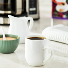 White coffee cups with dark brewed coffee, next to green mug
