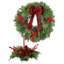 Fresh holly wreath set with red plaid bow, pinecones, and red berries; includes candle centerpiece