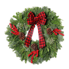 Fresh holly wreath with red plaid bow, red berries, and pinecones, angled view