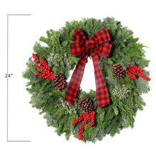 Fresh holly wreath with red plaid bow, red berries, and pinecones, close-up