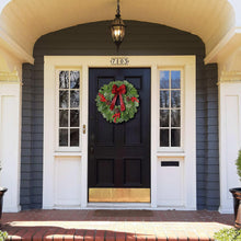 Fresh holly wreath centerpiece with red plaid bow and red berry clusters on door