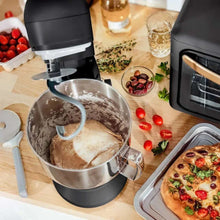 Black stand mixer with mixing bowl containing batter and whisk attachment