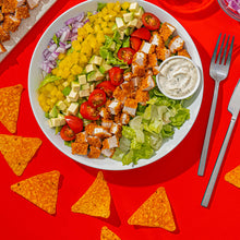 Plate of nacho-style salad with chips, lettuce, tomatoes, onions, and ranch