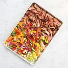 Natural aluminum baking sheet with sliced meat and mixed peppers