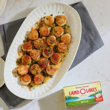 Salted butter half sticks pack with a white oval dish of sliced cooked pieces
