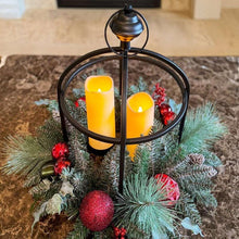 Evergreen centerpiece with two glowing LED candles and red ornaments in black lantern