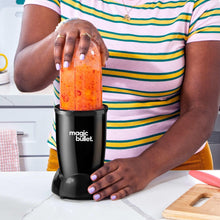 Black personal blender with clear cup, blending jar lid, and orange smoothie puree
