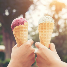 Two ice cream cones held in hands, with pink and vanilla scoops