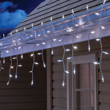 Cool white LED icicle lights hanging along a roof eave