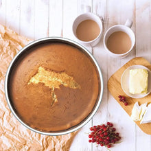 Round stainless steel cake pan with baked cake layer inside