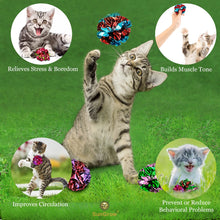Gray kitten on grass with several multicolor mylar crinkle balls toy pieces
