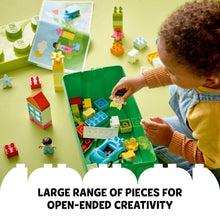 Open green LEGO DUPLO storage box with child playing among colorful bricks