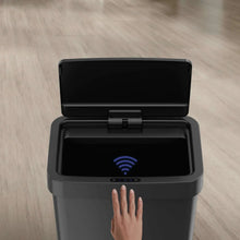 Black plastic automatic motion sensor trash can with open lid and hand in front