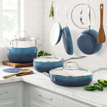 Denim blue ceramic non-stick pots and pans with stainless lids, hanging utensils, and wooden tools