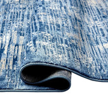 Blue area rug edge detail with distressed pattern and bound border, low pile