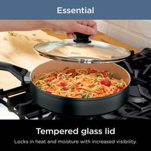 Black non-stick frying pan with tempered glass lid, cooking pasta