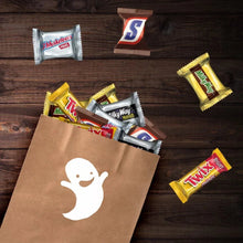 Mini chocolate candy bars around a brown paper bag on a wooden tabletop