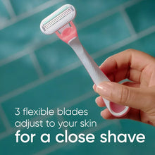 Women’s disposable razor with pink handle and metal cartridge, held in hand.