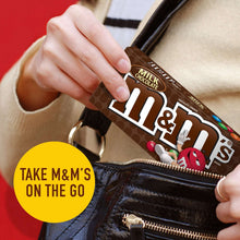 Milk chocolate candy box in hand, held over a dark bag