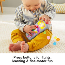 Toddler holding a gray learning remote toy with colorful buttons and a red top