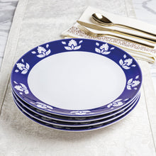 Indigo blue dinner plates stacked with white floral ring around the center