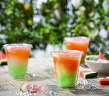 Disposable plastic cups with lids and straws, green and orange layered drinks