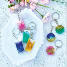 Epoxy resin keychains with blue, teal, pink and gold glitter pendants on metal rings