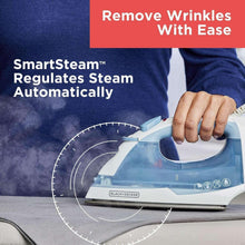 Steam iron pressing wrinkles on dark fabric with steady soleplate contact