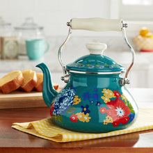 Teal enamel tea kettle with colorful floral print, white lid knob and arched metal handle.
