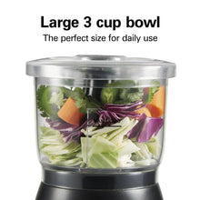 Clear 3-cup bowl filled with chopped vegetables on black food chopper base