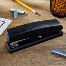 Black desktop stapler on desk with staple strip visible
