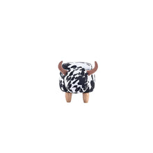 Cow-print cube ottoman with small brown horns and four short wooden legs