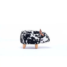 Cow-print ottoman, side view, rounded top with brown horn details and wooden legs